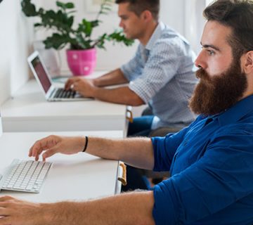 Two men working at computers in office 